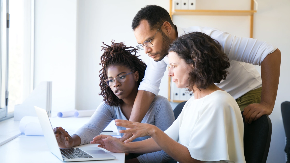 3 employees looking at laptop screen together
